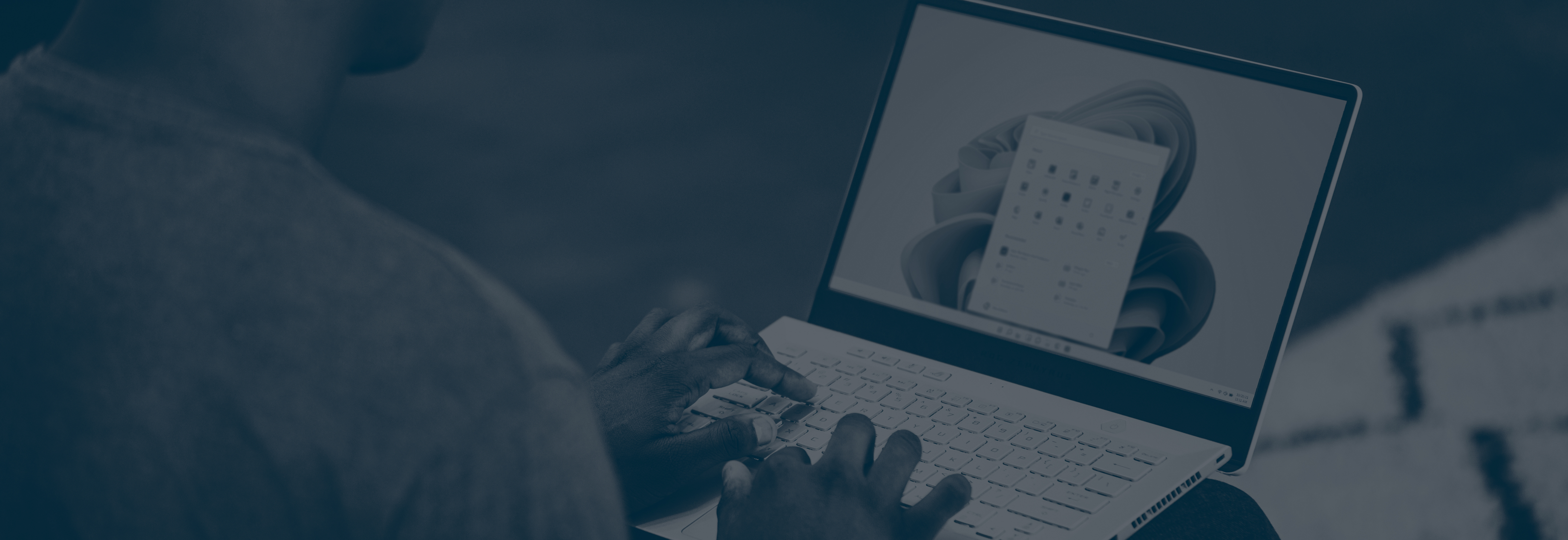 Hands typing on a laptop displaying the Microsoft Quick Assist remote support interface on Windows 11